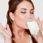 Young brunette woman drinking a glass of milk