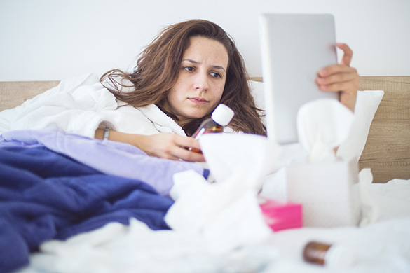 sick-woman-in-bed-on-tablet