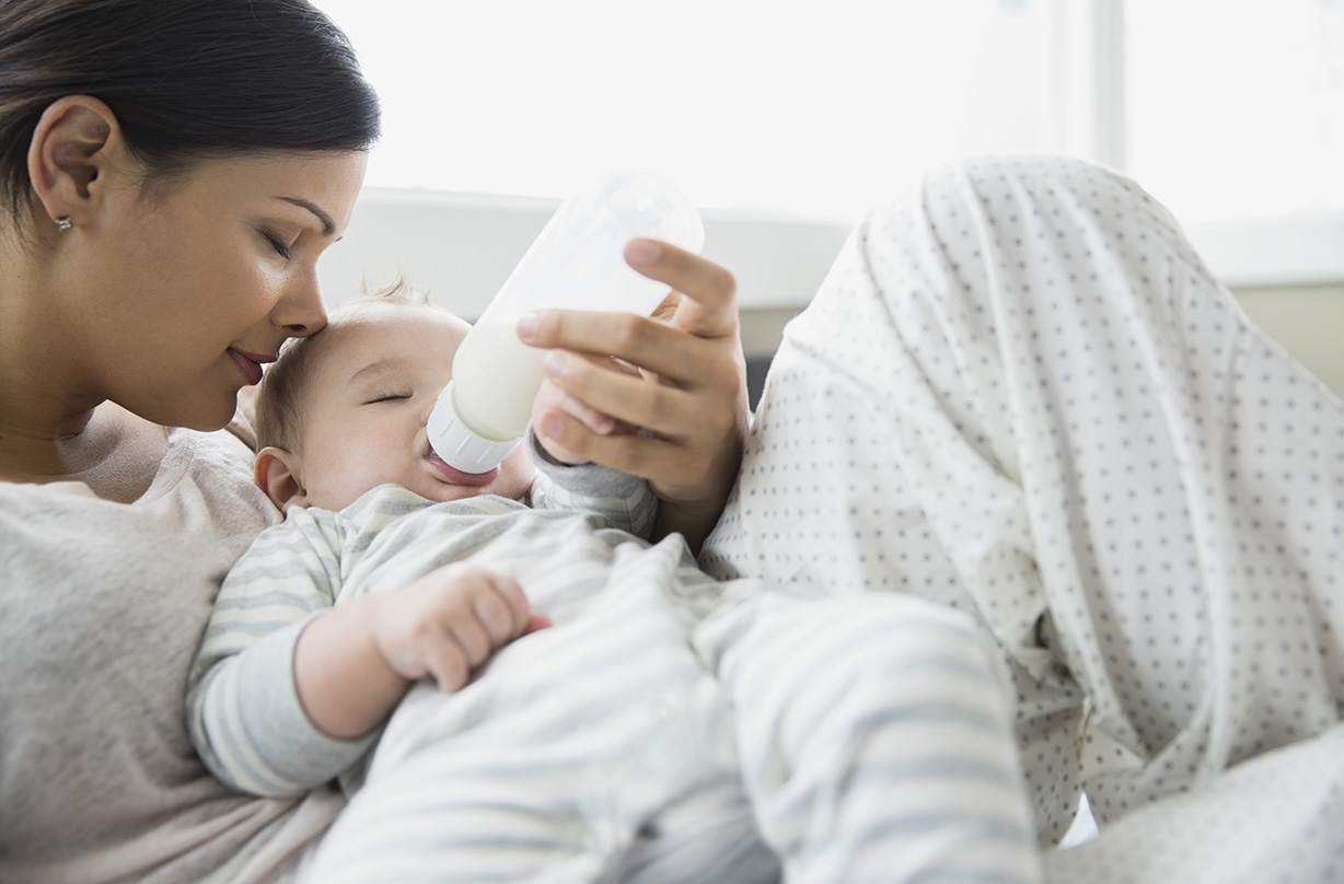 Serene mother feeding baby on bed